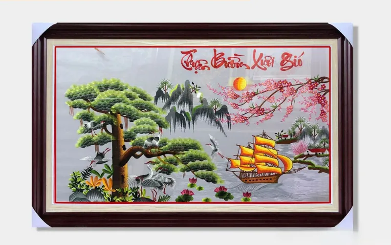 Một bức tranh thêu phong thủy với hình ảnh cây tùng, chim hạc, thuyền buồm và mặt trời, mang ý nghĩa "Thuận buồm xuôi gió"