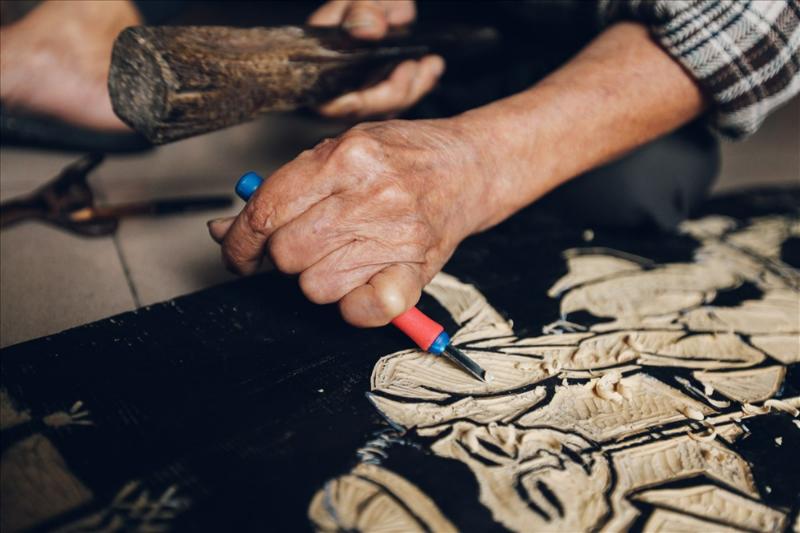 Nghệ nhân đang thực hiện công đoạn khắc gỗ sắc sảo