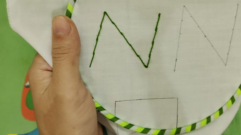 Bàn tay của một nghệ nhân đang tỉ mỉ thêu nối đầu các nét