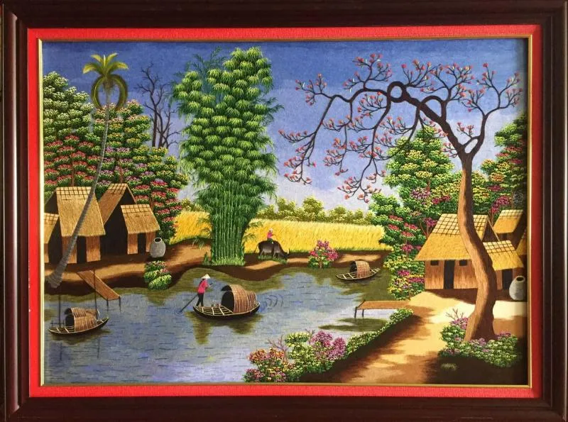 Một bức tranh thêu phong cảnh làng quê yên bình với những ngôi nhà mái tranh bên bờ sông